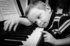 Un enfant qui joue du piano avec sa main gauche