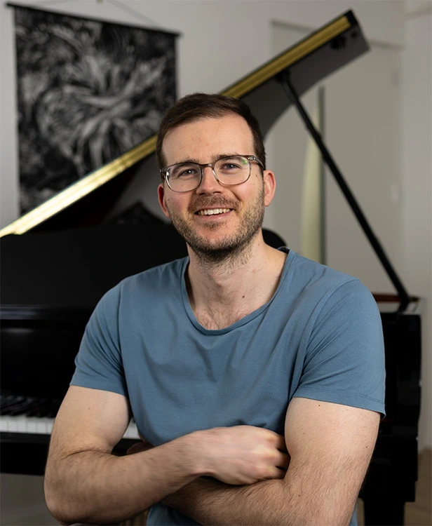Alexandre Desbois, professeur de piano à Nancy est devant le piano à queue où se déroulent les cours de piano.
